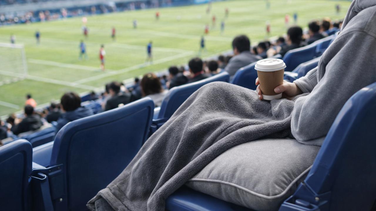 スタジアムの座席でひざ掛けとクッションを使い快適に観戦しているイメージ